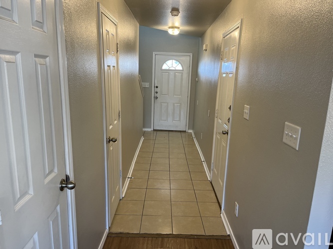 A hallway with white doors and a tiled floor.
