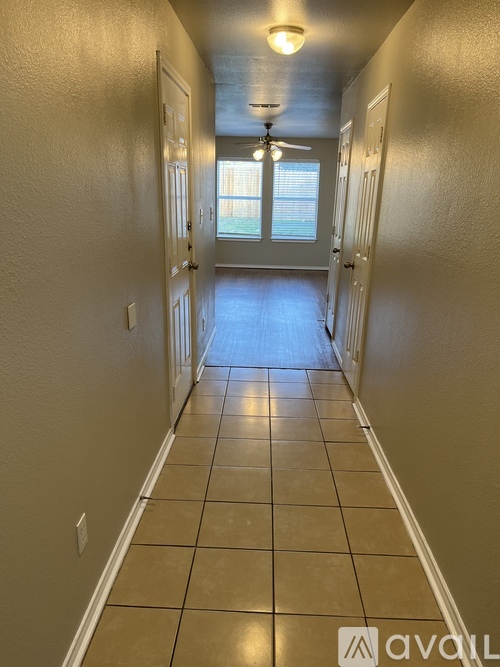 A long hallway with tiled floors and white walls.