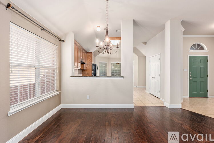 A spacious living room with hardwood floors and a chandelier.