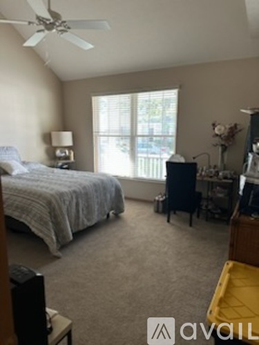 A bedroom with a bed, a chair, a television, and a window.