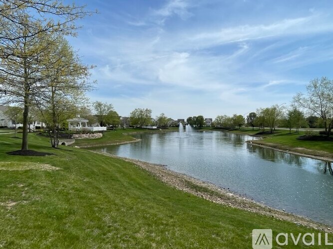 A serene park with a lake, trees, and a clear sky.
