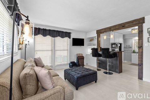 A living room with a brown couch and a black ottoman.