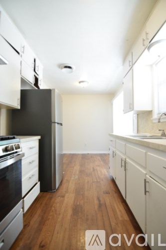 A kitchen with a black refrigerator and white cabinets.