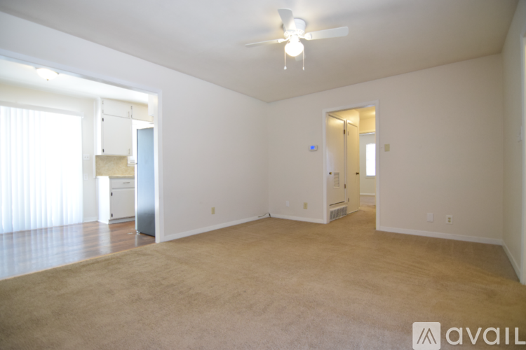 A spacious living room with a carpeted floor and a ceiling fan.