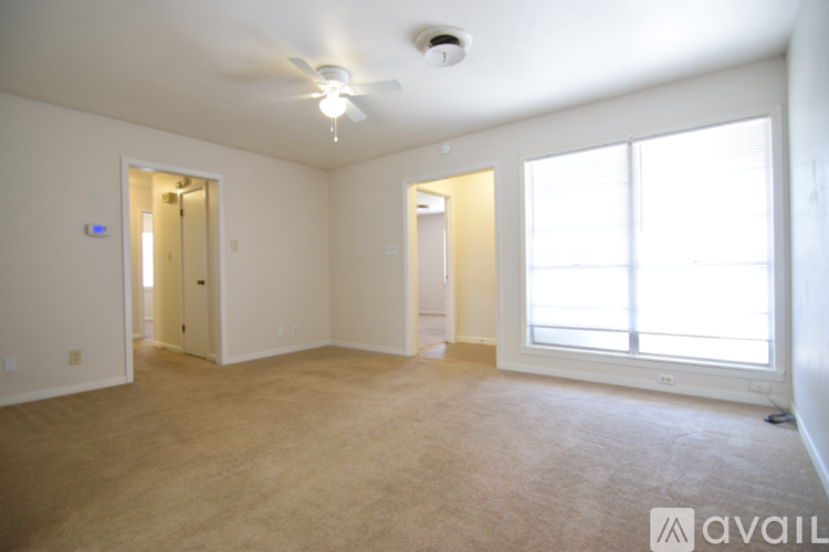 A spacious room with a ceiling fan and carpeted floor.