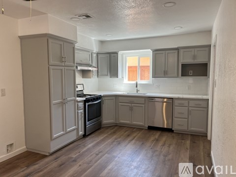 A kitchen with wooden floors and grey cabinets.