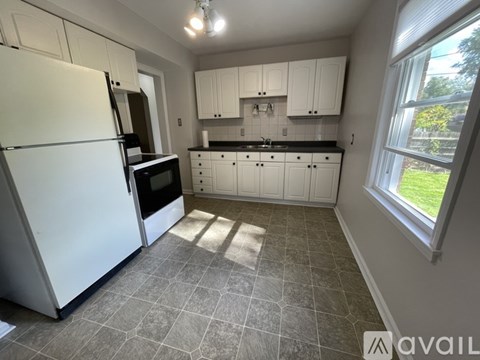 A kitchen with a white refrigerator and black countertops.