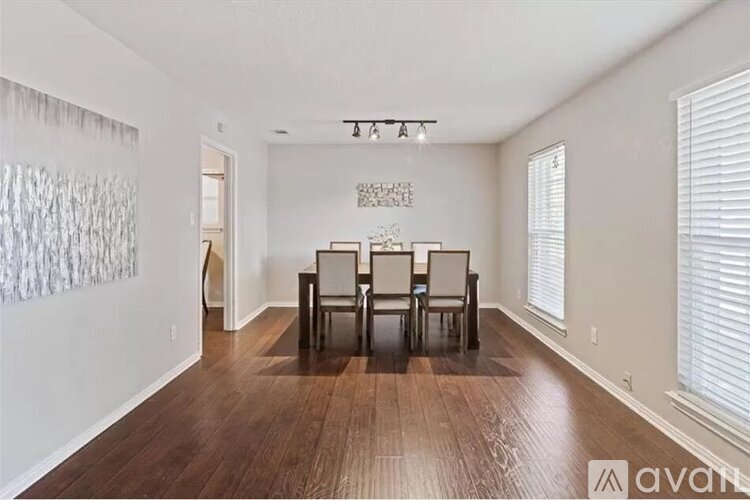 A living room with a wooden floor and a glass table with chairs.