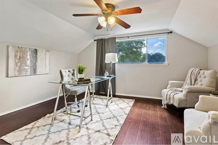 A room with a ceiling fan, a glass table with chairs, and a window with a view of trees.