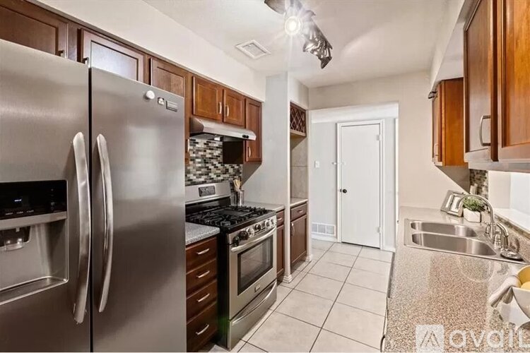 A kitchen with a stainless steel refrigerator, stove, and sink.