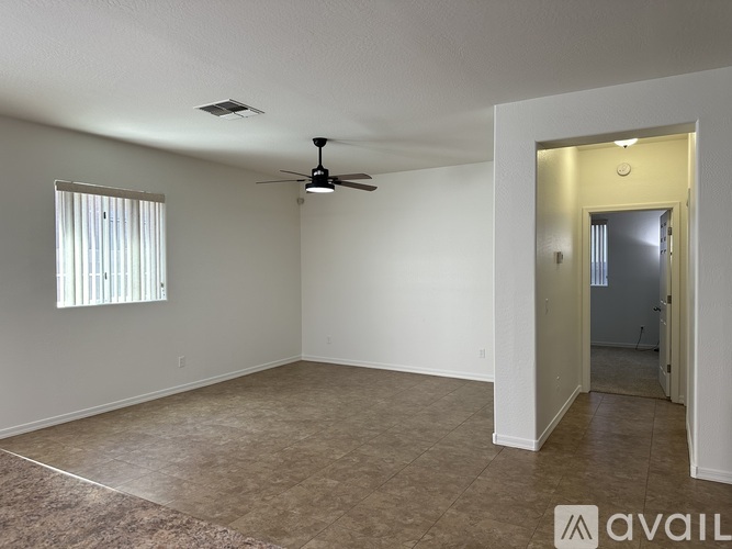 A spacious room with a ceiling fan and a door leading to another room.