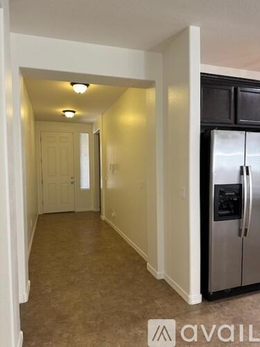 A kitchen with a refrigerator and a doorway leading to another room.