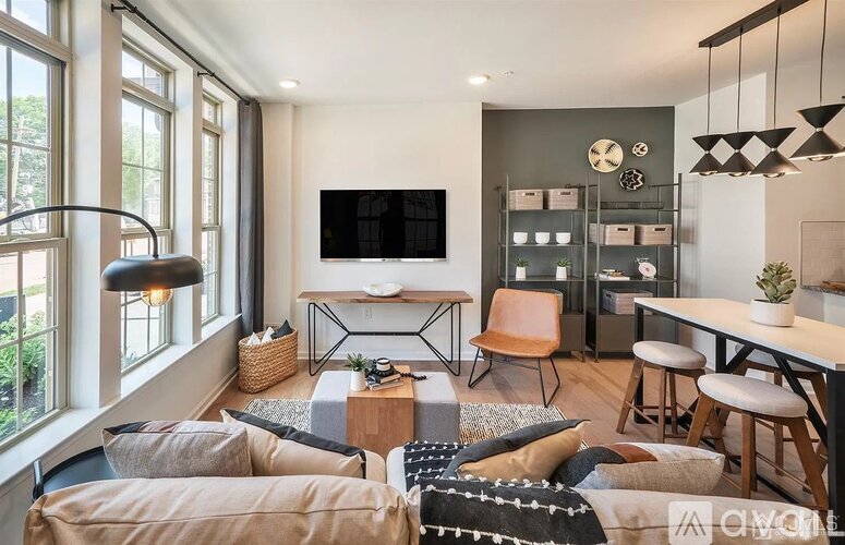 A living room with a large window, a flat screen TV, a sofa, a coffee table, and a rug.