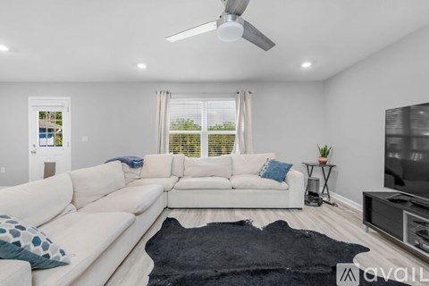 A living room with a white couch and a black rug.