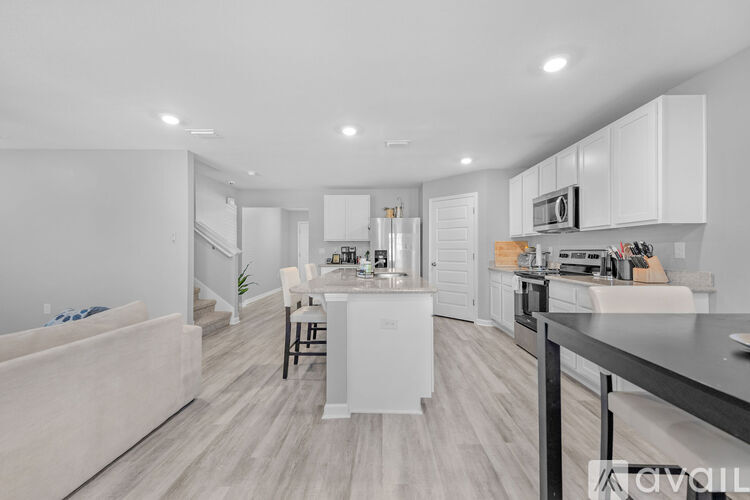 A modern kitchen with white cabinets and a wooden floor.