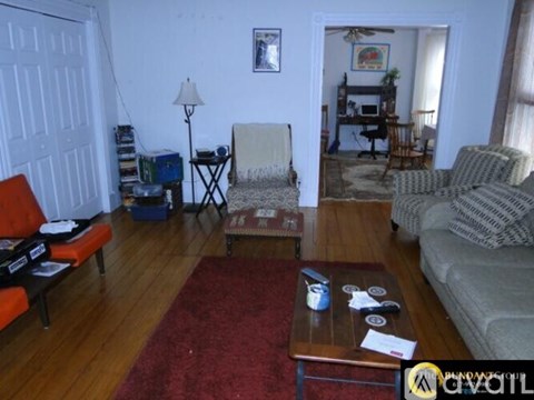 A living room with a red rug and a grey couch.