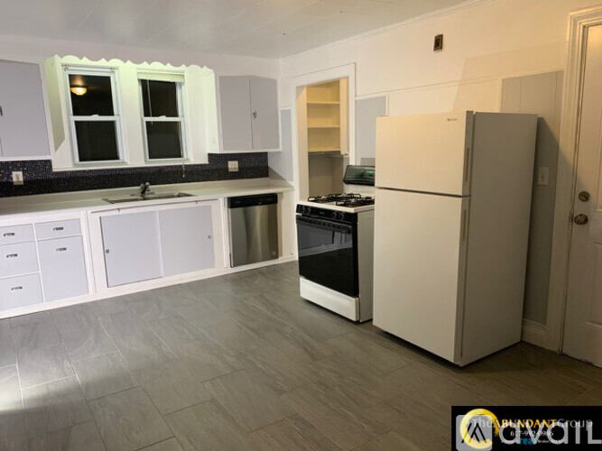 A kitchen with white cabinets and a white fridge.