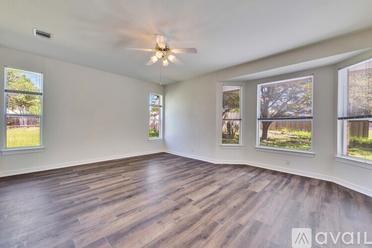 A spacious room with wooden flooring and a ceiling fan.