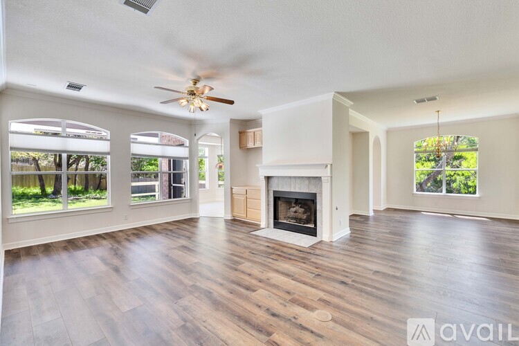 A spacious living room with a fireplace and a ceiling fan.