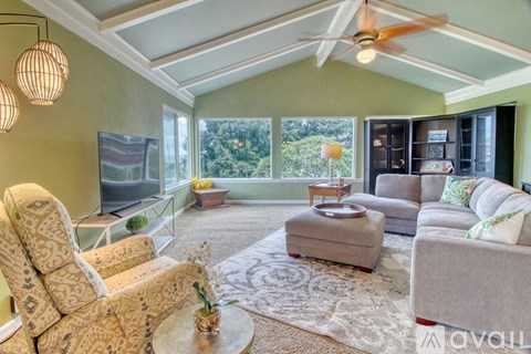 A living room with a patterned chair and a grey ottoman.