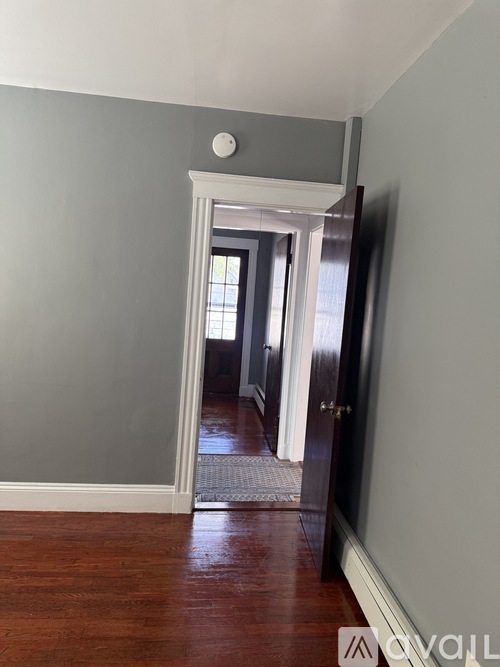 A hallway with a wooden floor and a door leading to another room.