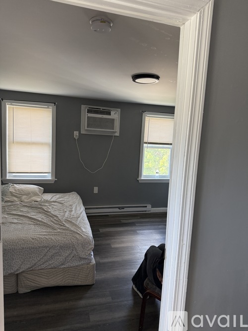 A bedroom with a bed, window, and a wall-mounted TV.