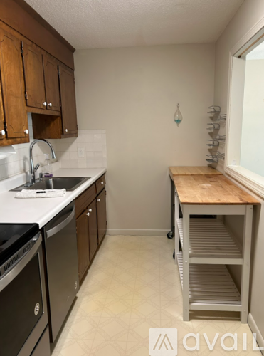 A kitchen with a sink, dishwasher, and a wooden cart.