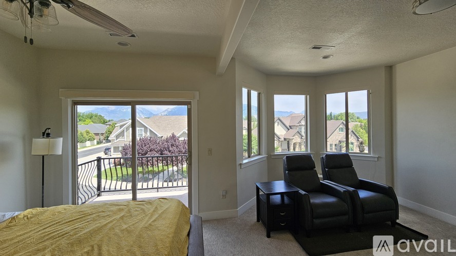 A bedroom with a bed, two chairs, and a table with a window view.