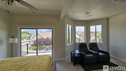 A bedroom with a bed, two chairs, and a table with a window view.