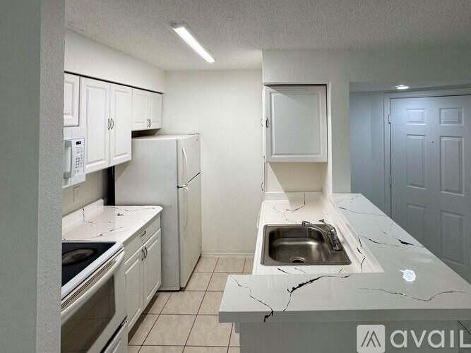 A kitchen with white cabinets and a marble countertop.