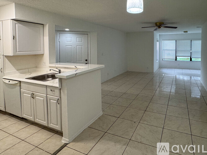 A kitchen with white cabinets and a marble floor.