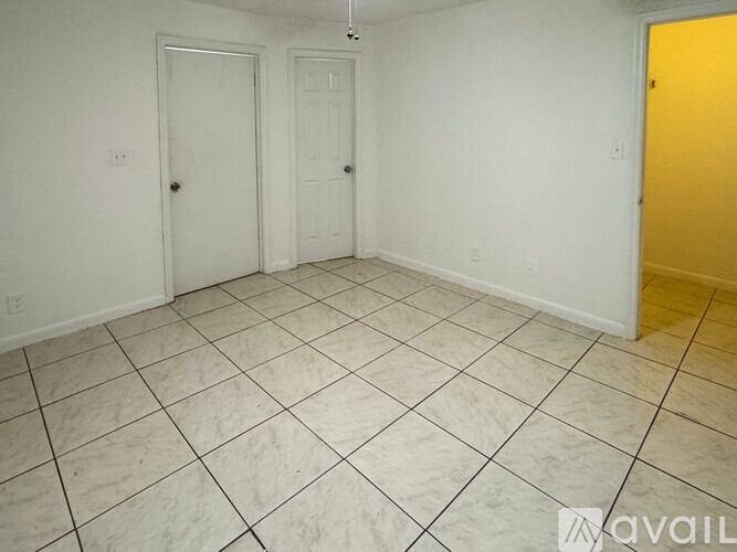 A room with white walls and a tiled floor with three doors.