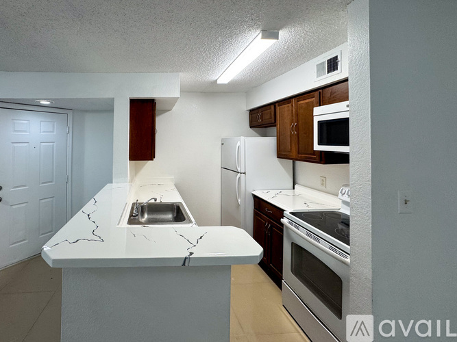 A kitchen with white appliances and a marble countertop.
