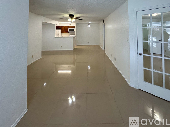 A spacious room with a kitchenette in the background and a door on the right.
