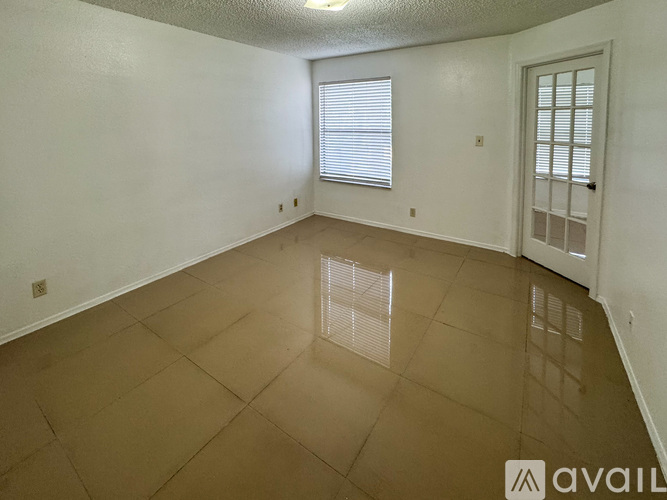 A spacious room with a tiled floor and a door on the right.
