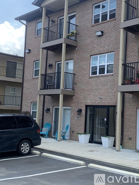 A black van is parked on the street in front of a brick apartment building.