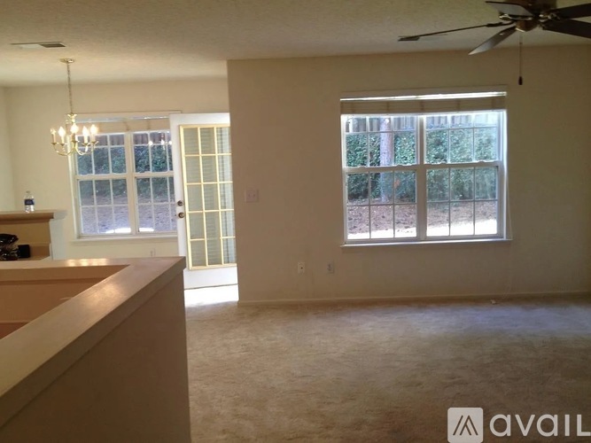 A room with a fan, a chandelier, and a window with blinds.