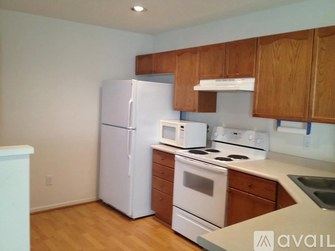 A kitchen with white appliances and wooden cabinets.