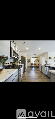 A modern kitchen with white cabinets and a wooden floor.