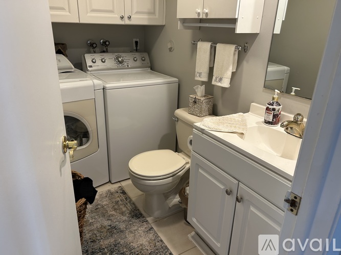 A bathroom with a toilet, sink, and washer and dryer.