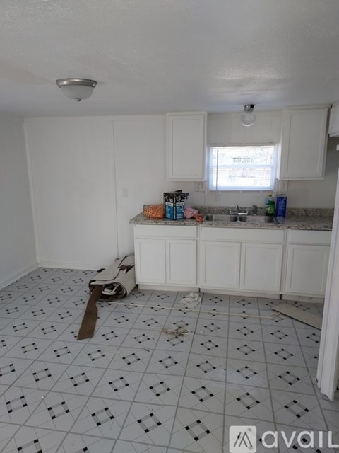A kitchen with white cabinets and a tiled floor.