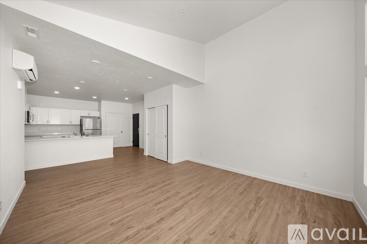A spacious room with wooden flooring and white walls.