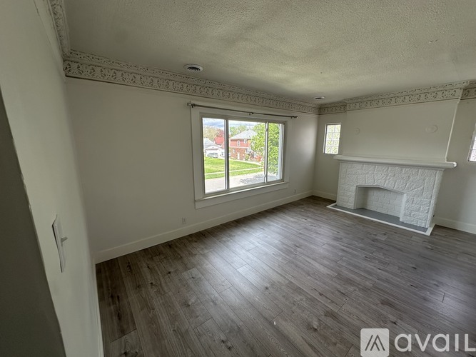 A spacious room with wooden floors and a fireplace.