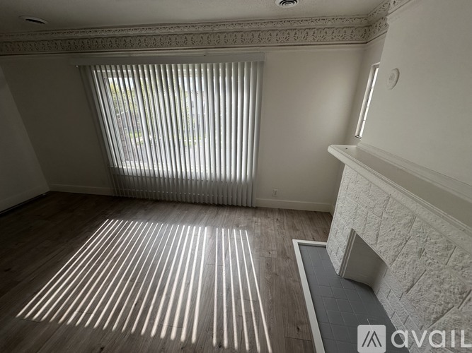 A room with a fireplace and a window with blinds.