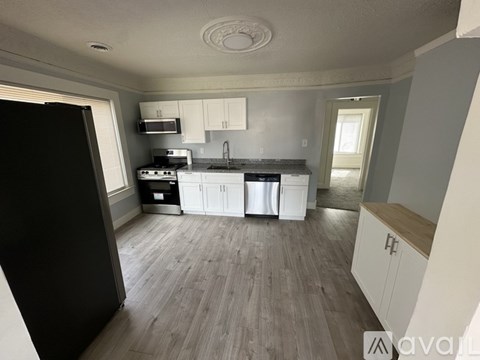 A kitchen with white cabinets and a black refrigerator.