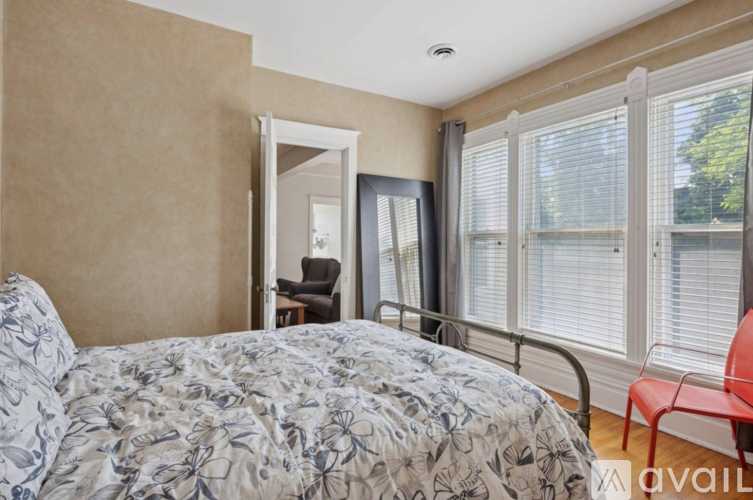 A bedroom with a bed, chair, and window.