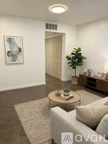 A living room with a couch, coffee table, and a painting on the wall.