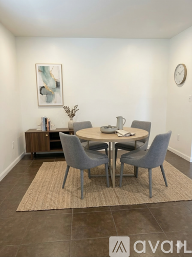 A dining room with a round table and grey chairs.