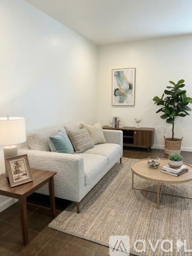 A living room with a white couch, a wooden coffee table, and a potted plant.