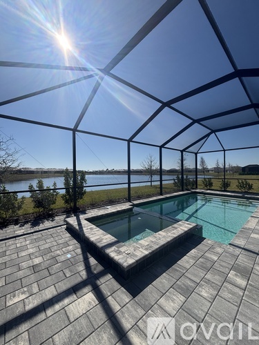 A pool enclosed by a glass wall with the sun shining through.